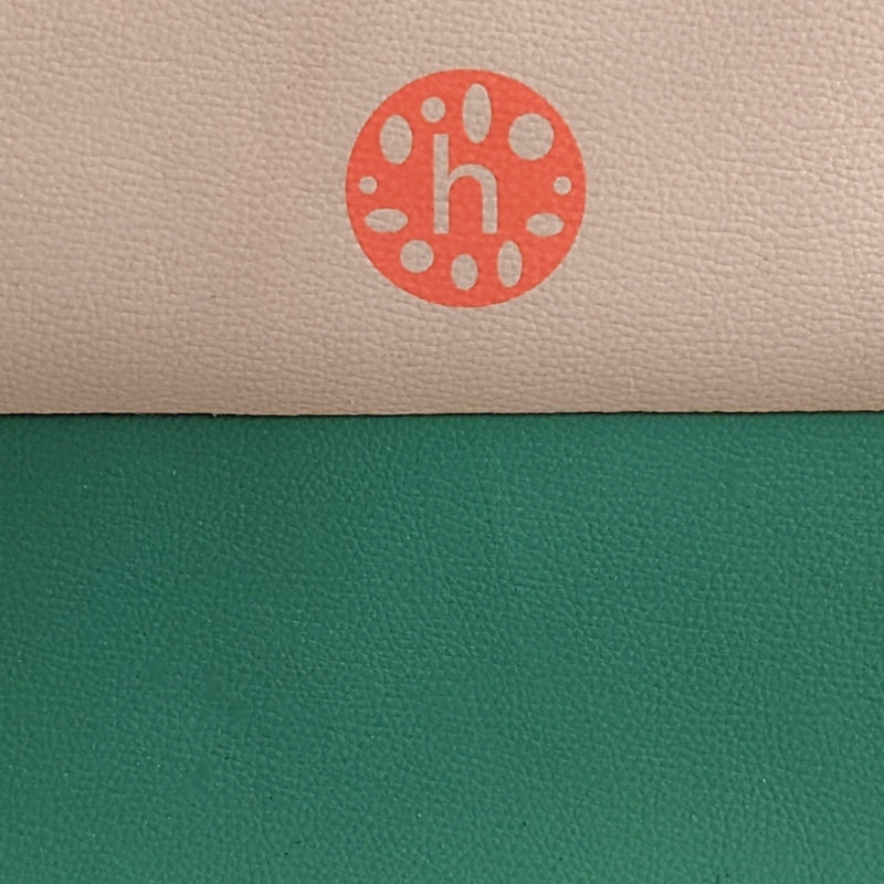 Close-up of vegan leather play mat featuring peach and green colors with a logo detail.
