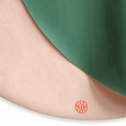 Close-up of a vegan leather play mat, showcasing the round design with green and soft pink colors.
