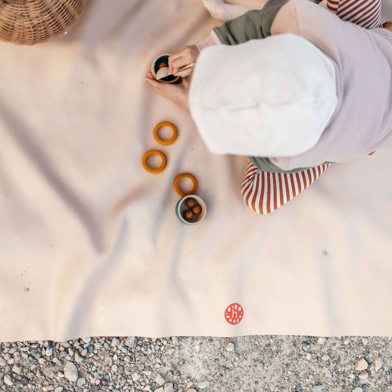 A child playing with colorful rings on an extra large waterproof silicone mat, Gallivant Mat (XL) outdoors.