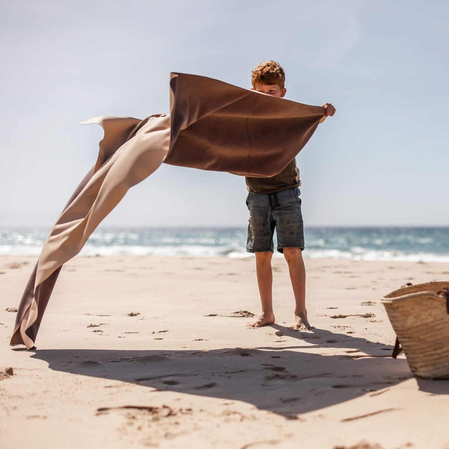 Garçon tenant le tapis de pique-nique familial en silicone Gallivant XL à la plage, tapis de jeu extérieur imperméable extra-large