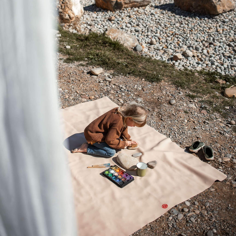 Child creating art on an extra large waterproof silicone mat, Gallivant Mat, outdoors with nature background.