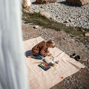 Child creating art on an extra large waterproof silicone mat, Gallivant Mat, outdoors with nature background.