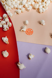 Large round waterproof play mat with scattered popcorn on colorful surfaces.