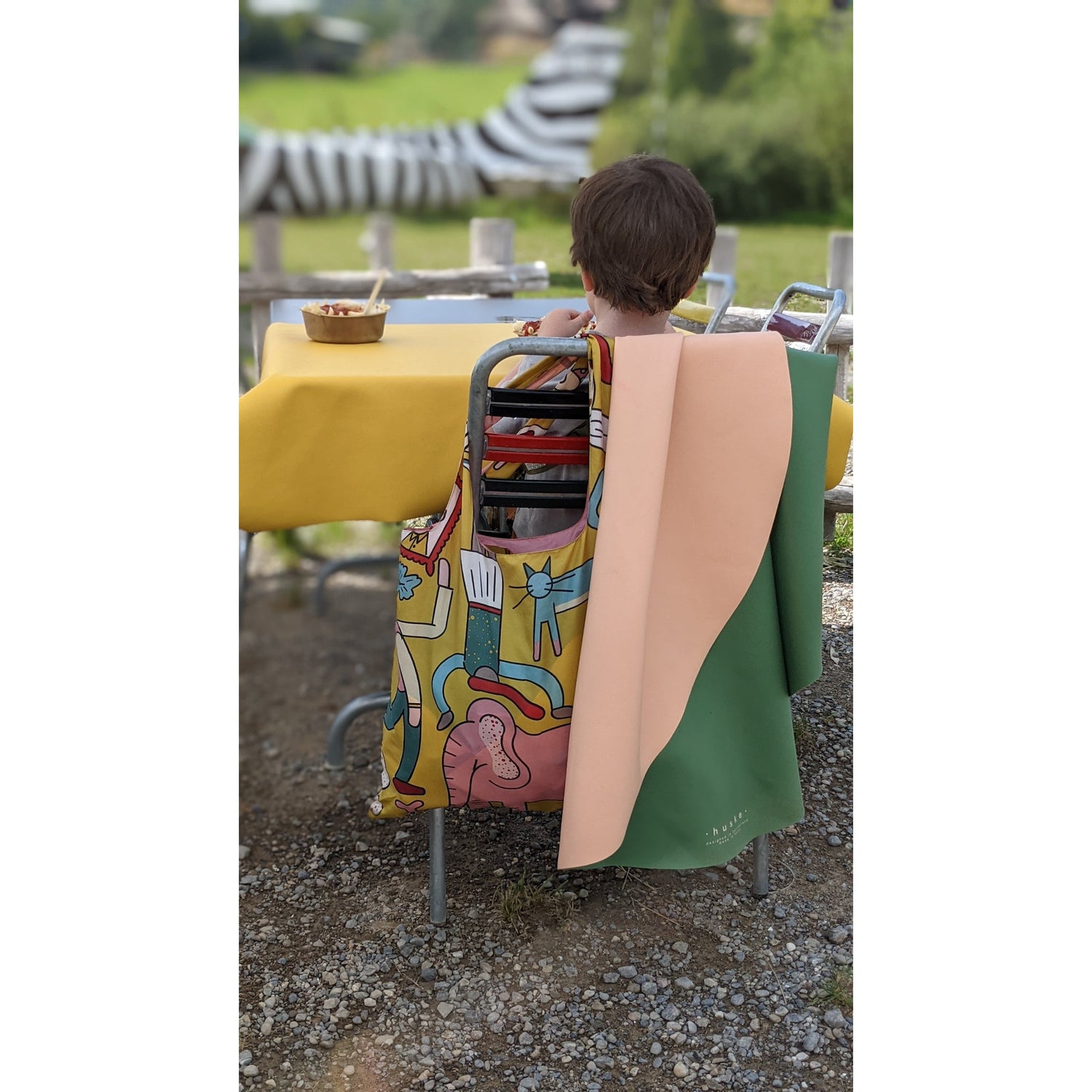 Child sitting at a table with a limited edition LOQI tote bag illustrated by Clara San Millán.