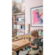 A child playing on a waterproof silicone leather changing mat, Wriggle Mat (S), featuring toys and a cozy home setting.