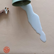 Waterproof silicone leather changing mat with spilled milk and a toy giraffe beside it.
