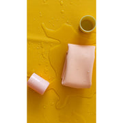 Waterproof silicone leather changing mat on yellow background with droplets of water.