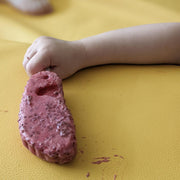Child's hand holding colorful play dough on a waterproof silicone leather changing mat.