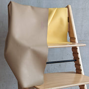 Waterproof silicone leather changing mat draped over a wooden chair, showcasing its smooth texture and minimalistic design.