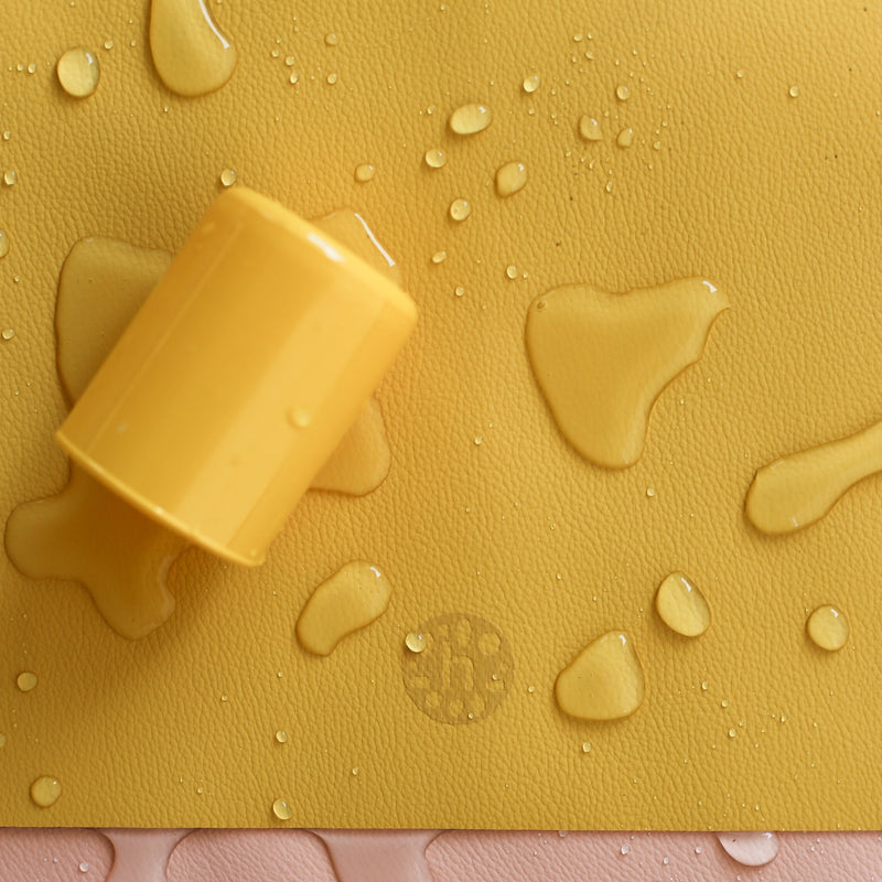 Waterproof silicone leather changing mat with water droplets and a yellow toy on top.