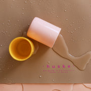 Waterproof silicone leather changing mat with spills from yellow and pink cups.
