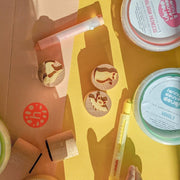 Colorful crafting supplies and wooden tokens on a bright yellow surface, ideal for creative play and activities.