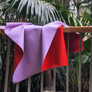 Waterproof square play mat for children, Roam Mat featuring a purple and red design draped over a railing.
