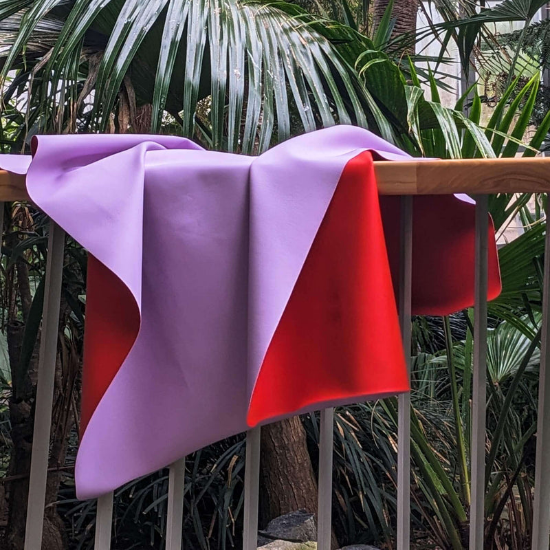 Waterproof square play mat for children, Roam Mat featuring a purple and red design draped over a railing.