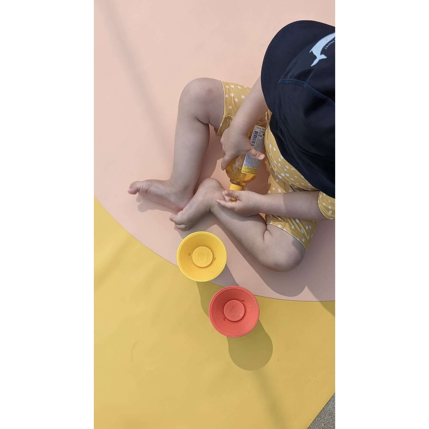 Kind spielt mit bunten Schalen auf Roam Square Silikonleder-Hochstuhlmatte, abwischbare Bodenmatte für drinnen Krabbelunterlage