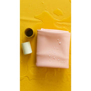 Waterproof square play mat for children in soft pink color, complementing a yellow background with water droplets.