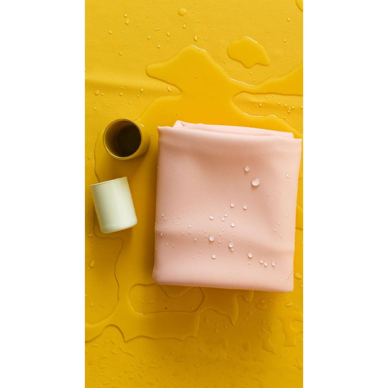 Waterproof square play mat for children in soft pink color, complementing a yellow background with water droplets.